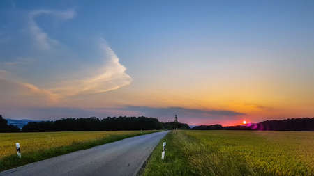 Sunset on a small country road, without center stripe, in a cornfield, near Bad Schandau, Saxony, Germanyの写真素材