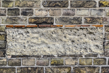 Old brick wall pattern closeup with rectangle of cement in the middle.の写真素材