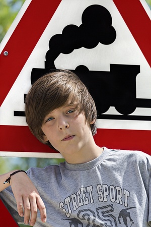 portrait of a cool boy in front of an locomotive traffic sign.の写真素材