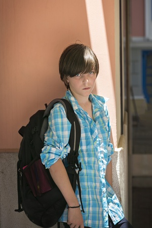 teen boy with rucksack on travel, leaning against a wall.の写真素材