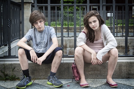 two dirty urban teens sitting on a wall.の写真素材
