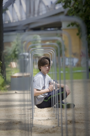 portrait of a teenager boy sitting behind a metal frame.の写真素材