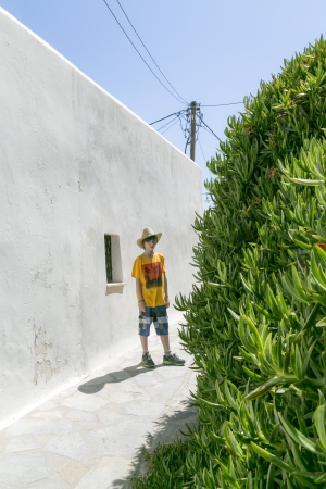 male teenager with straw hat standing behind a bush.の写真素材