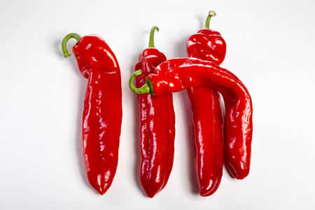 a group of red bell peppers on a white.の写真素材