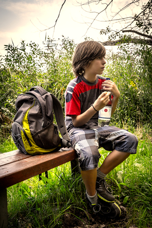 vintage style portrait of a teenager boy, having a break, while sitting on a bench.の写真素材