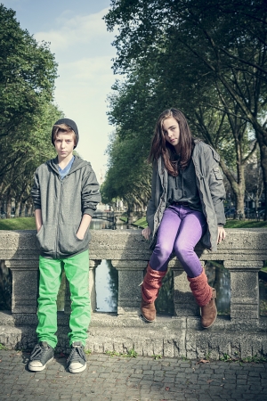 vintage style portrait of two teenager sitting on a bridge.の写真素材