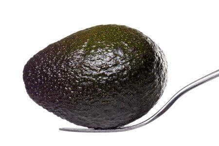 an avocado laying on a fork, isolated on white.の写真素材