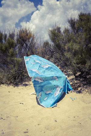 old blue parasol  half buried at the beach.の写真素材