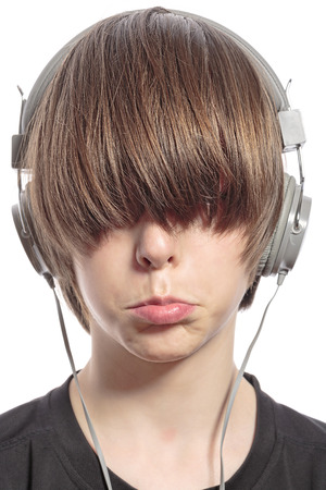 sulking cute teenager boy with hair over his eyes and headphones.の写真素材