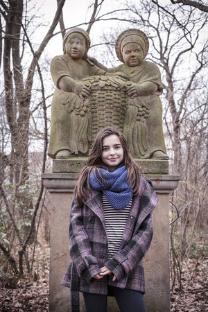 portrait of a beautiful female teenager in front of a sculpture in winter. Unknown artist of the 18th century.の写真素材