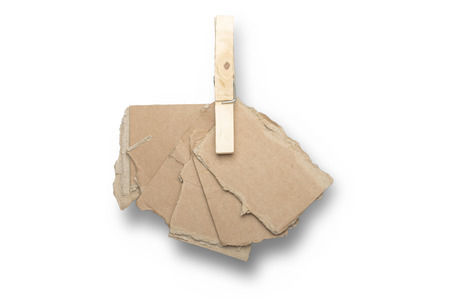 stack of ripped pieces of card board, holding together of a clothespin, isolated on white.の写真素材