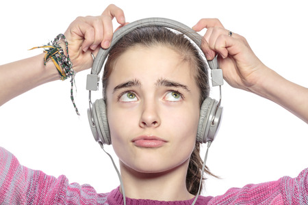 beautiful teenager girl fumble on her headphones, isolated on white.の写真素材
