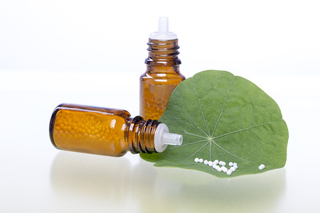 two bottles with homeopathy globules and green leaf.の写真素材