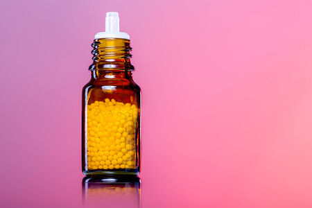 single bottles with homeopathy globules,white red background.の写真素材