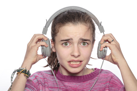 scared teenager girl with headphones,  isolated on white.の写真素材