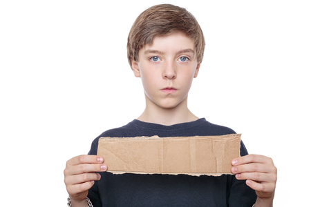 portrait of a teenager boy holding a brown piece of cardboard in front of his chest.の写真素材