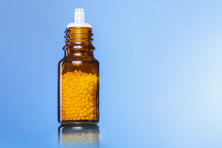 single bottle with homeopathy globules with blue background.の写真素材