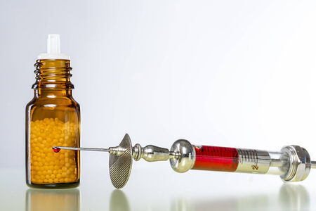 still life with homeopathy globules and syringe with blood.の写真素材