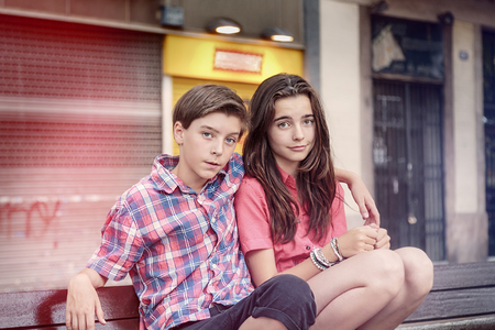 toned image of two siblings crouching on a benchの写真素材