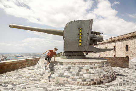 Castell de Montbejuic Barcelona, boy is jumping in front of a cannonの写真素材
