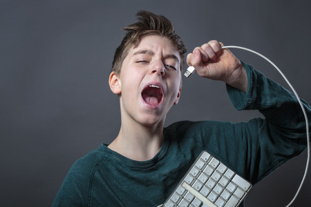 singing teenage boy with computer keyboard and gray background for fast isolatingの写真素材