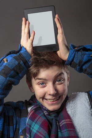 smiling mad boy holding a tablet computer on his headの写真素材