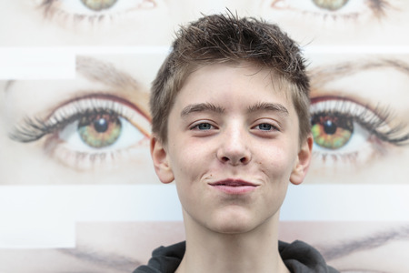 portrait of a teenage boy with eye pattern in backgroundの写真素材