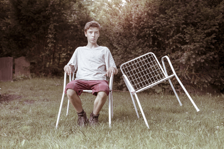 lonely teenage boy with two chairsの写真素材