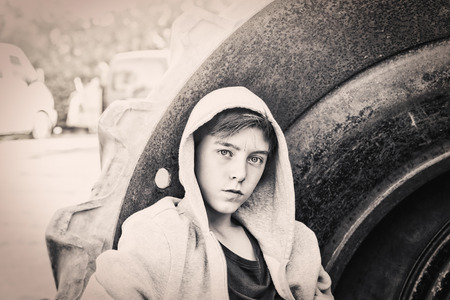 portrait of a teenage boy leaning against a huge tireの写真素材