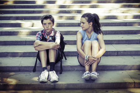 tired travelling siblings sitting on stepsの写真素材