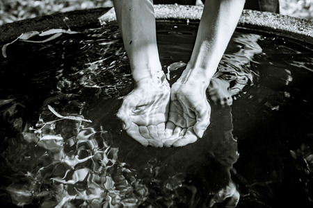 Holding water from a well  in cupped hands, black and white shot