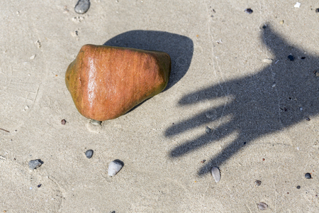 shadow of a hand and wet pebble at the beachの写真素材