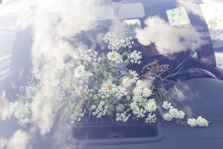 bouquet of field flower behind a windshield in a carの写真素材