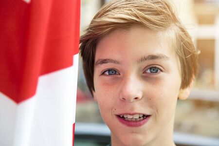 portrait of a smiling boy with red and white flag besideの写真素材