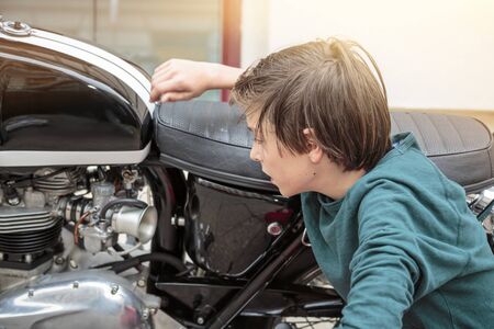 teenage boy examines a motorcycleの写真素材