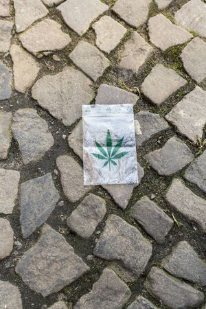 cannabis leaf printed on a small plastic bag laying on the pavementの写真素材