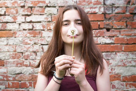 portrait of a smiling young woman holding a dandelionの写真素材