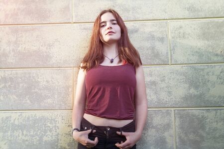 Portrait of a cool young woman in front of a grungy wall