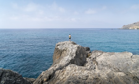 young man standing on a cliffの写真素材