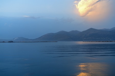 ocean landscape with an orange glowing cloud above a mountain rangeの写真素材