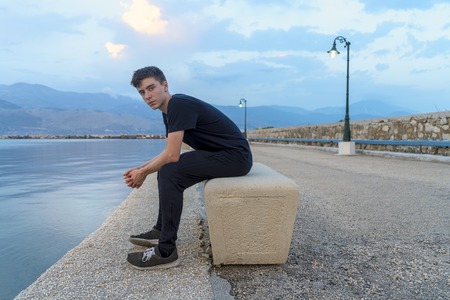 portrait of a young man sitting on a pierの写真素材