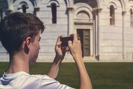 young man taking a photo of the leaning tower of Pisa, Italyの写真素材