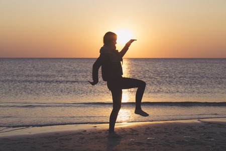 sunset over the sea, woman is dancing on the beachの写真素材