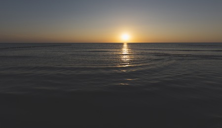 sunset over the horizon of the ocean with cloudless skyの写真素材