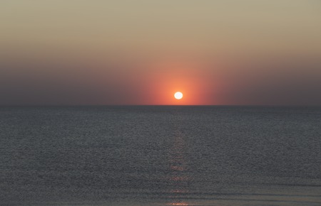 sunset over the horizon of the ocean with cloudless skyの写真素材