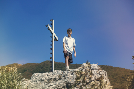 Italy Tuscany, young man is standing next to a summit crossの写真素材