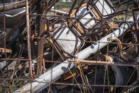 Rusty metal trash and chairs behind a fenceの写真素材