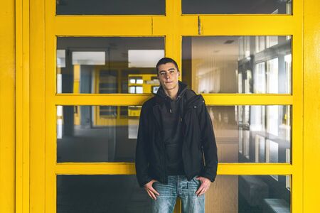 portrait of a casual young man in front of yellow windowsの写真素材