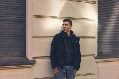 portrait of a smiling young man in front of an old house