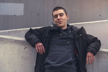 portrait of a smiling young man leaning against a concrete wallの写真素材